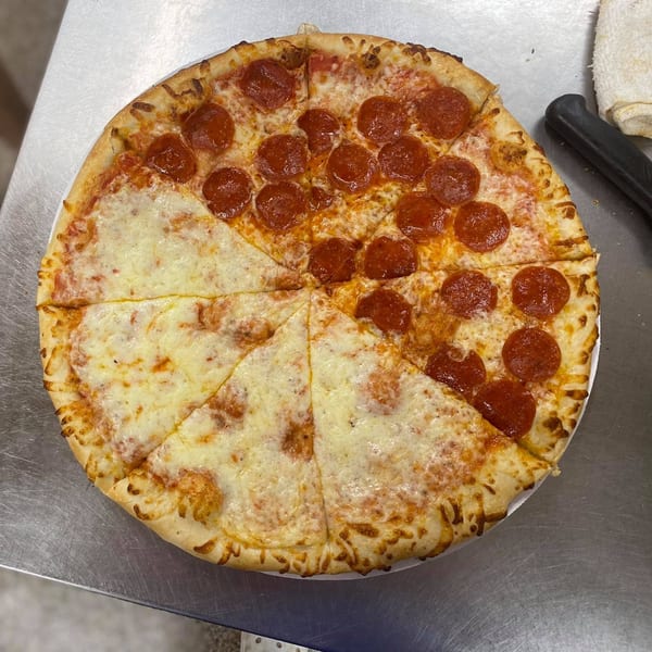 A half pepperoni, half cheese pizza from Pizzeli's Italian Oven on a metal counter.